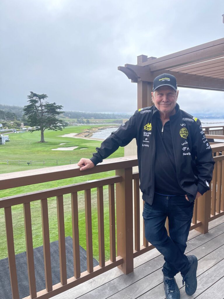 Golfer poses on a deck overlooking golf course.