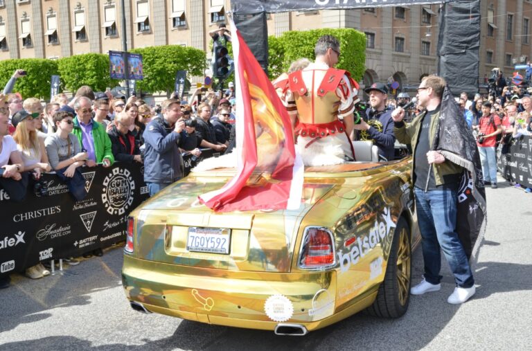 A man dressed as a Roman emperor drives a gold Rolls-Royce.